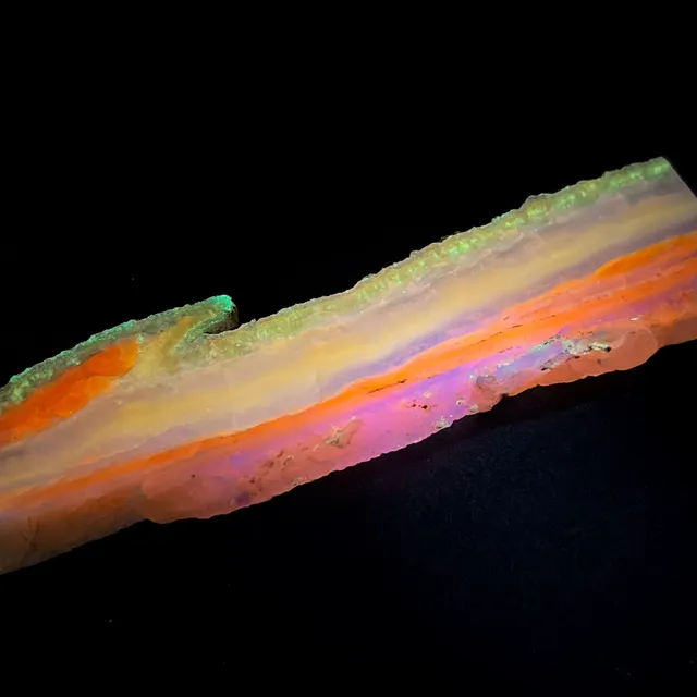 Hokkaidoite slice 2AL03 under UV light (3/10) — 11.4 × 3.1 × 0.9 cm, Hokkaido, Japan · Kitsune Mineral