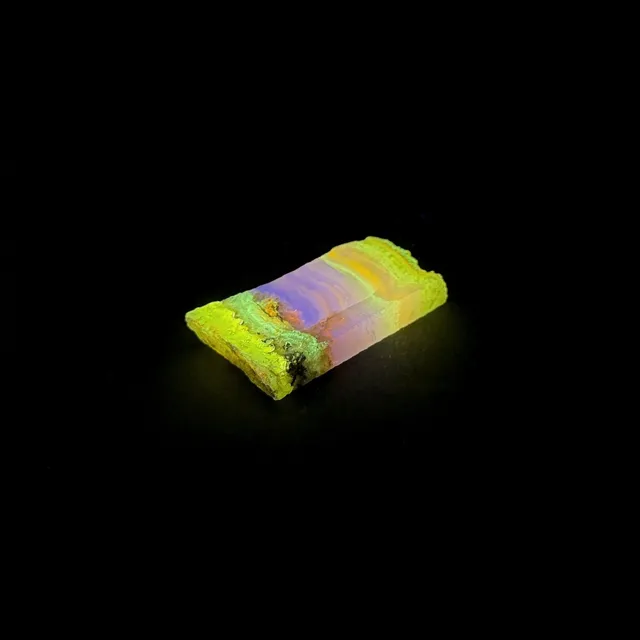 Hokkaidoite slice 2C11 under UV light (3/9) — 4.0 × 2.1 × 0.65 cm, Hokkaido, Japan · Kitsune Mineral